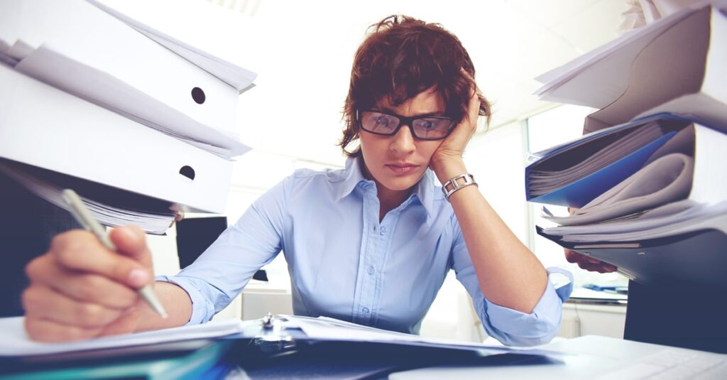 2024.09_Blog_Update-2020_7-questions-prioritize-work woman overwhelmed who needs to review these 7 questions to prioritize your workload