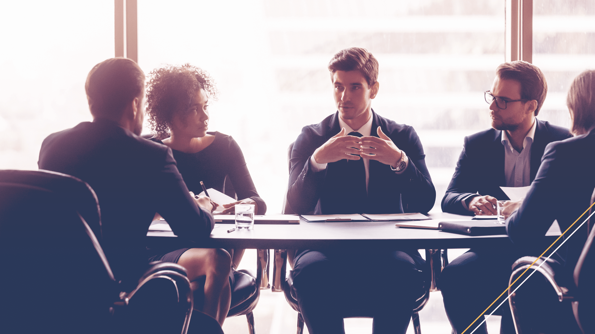 Image of leader with strong executive presence projecting authority and speaking to team at table