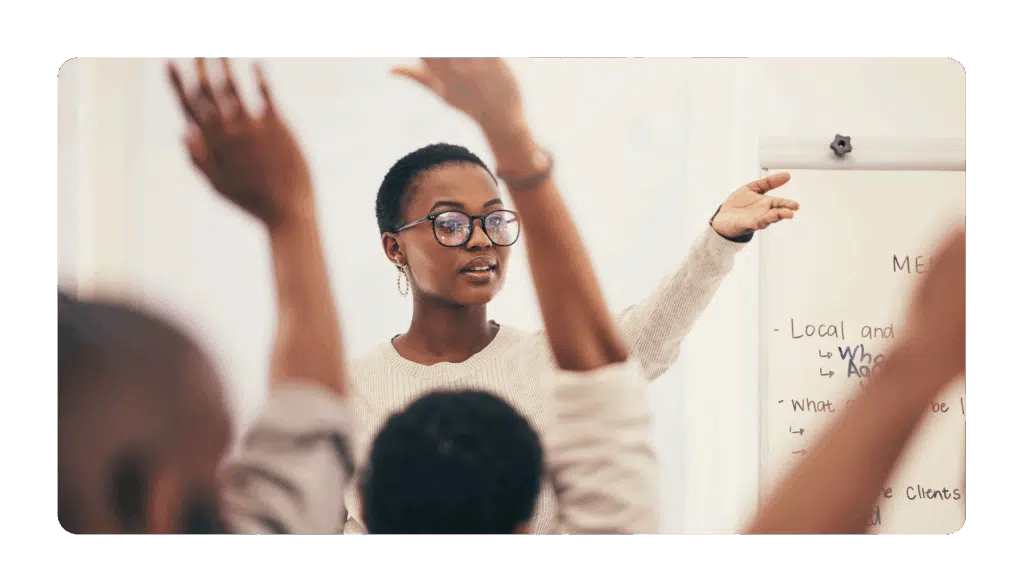 offsite facilitator standing in front of team with hands raised to participate